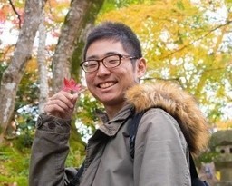 もみじを持って微笑む男性